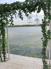 wedding arch with white lanterns on the shore of a picturesque lake