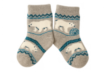 Pair of children's warm fuzzy socks with polar bear and igloo pattern, winter clothing concept on transparent background