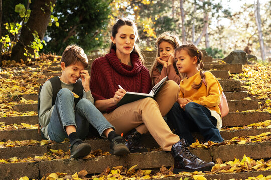 Energetic teacher leads a small, diverse group of preschoolers on an outdoor nature exploration, pointing out interesting details of the local flora and fauna. - Powered by Adobe