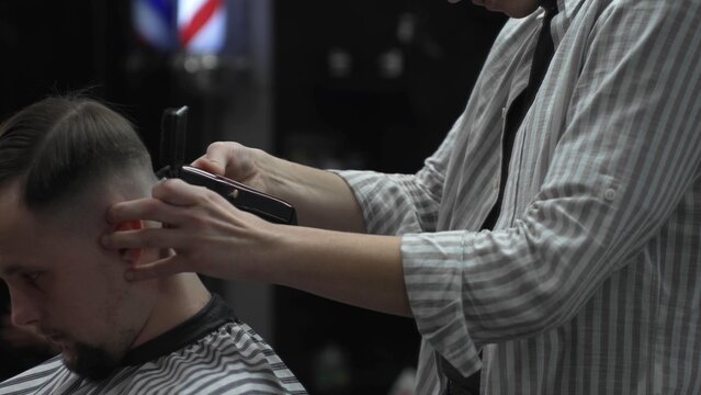Professional barber carefully combing client's hair, preparing precise hairstyle with expert grooming techniques in modern barbershop setting