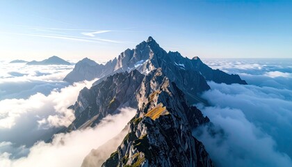 Jagged Mountain Peaks Above Soft Clouds Illuminated by Golden Sunlight Under a Clear Blue Sky