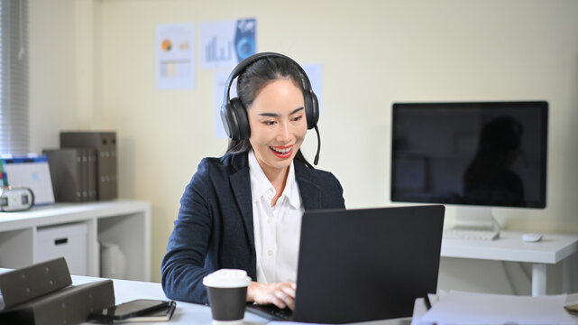 Smiling businesswoman wearing headset talking during online meeting, representing customer service support and communication in modern office