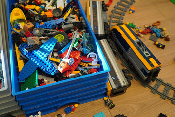 Naklejka premium A collection of colorful Lego bricks and train sets on a wooden surface