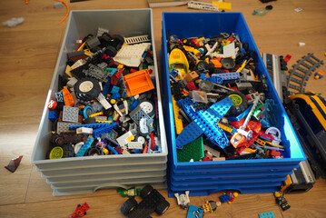 Naklejka premium Colorful collection of toy building blocks in storage bins on a wooden floor