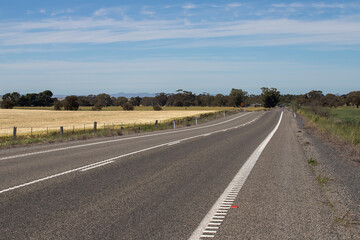 Rural highway and golden farmland under clear blue sky