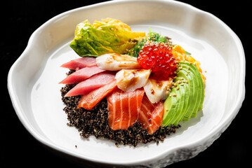 A vibrant poke bowl with fresh salmon, tuna, avocado, corn, and fish roe over black quinoa in a white dish on a black background
