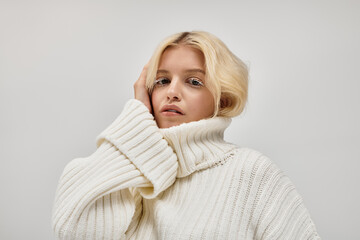 Cozy winter vibes with a beautiful young blonde woman in a knitted sweater
