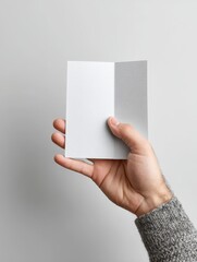 Hand Showing Bifold Brochure on White Surface