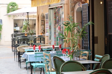 Outdoor café tables with turquoise chairs and checkered tablecloths)