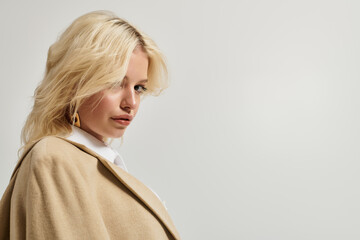 Stylish young woman in trendy winter attire poses in white studio setting