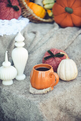 Pumpkin shaped mug of strong black coffee, cozy autumn interior with handmade decorations
