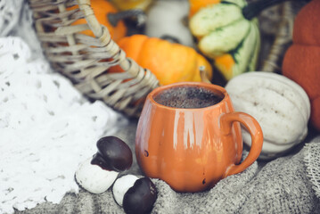 Pumpkin shaped mug of strong black coffee, cozy autumn interior with handmade decorations
