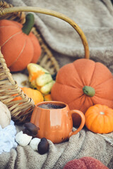 Pumpkin shaped mug of strong black coffee, cozy autumn interior with handmade decorations