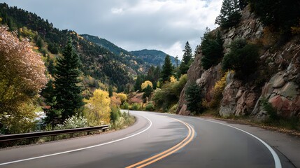 Fototapeta premium Winding mountain highway curves through a forested landscape during the autumn season