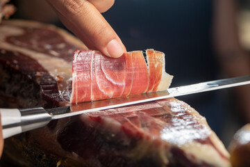 Slicing Iberian ham close up with knife