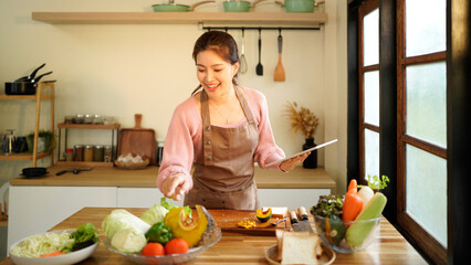 Tablet, kitchen and woman cooking recipe from website blog for home lunch, dinner or food. Digital...