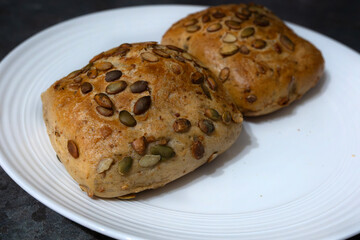 Freshly baked pumpkin seed rolls on a white plate ready to be served with a meal or enjoyed as snacks