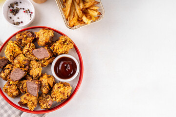 Beef Steak Nuggets Bites in crispy corn breading, cooked in an airfrier grill or oven. Healthy carnivore diet alternative nuggets. With barbecue sauce, spices and french fries potato chips