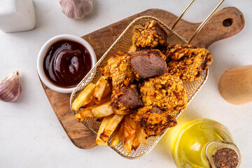 Beef Steak Nuggets Bites in crispy corn breading, cooked in an airfrier grill or oven. Healthy carnivore diet alternative nuggets. With barbecue sauce, spices and french fries potato chips