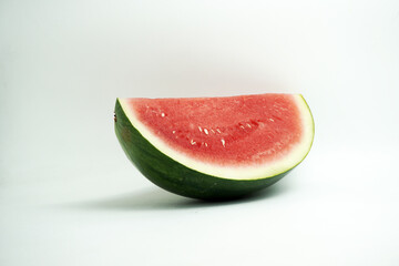 Close-up of a refreshing wedge of ripe red watermelon showing seeds and green rind, isolated on a clean white background, perfect for summer themes.