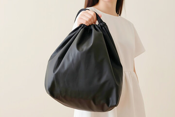 Person holding a sleek black drawstring bag, ideal for carrying everyday essentials, shopping, or gym gear with minimalist style.