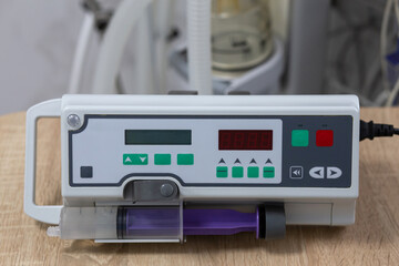 A syringe infusion pump is on the table. Against the background of medical equipment.