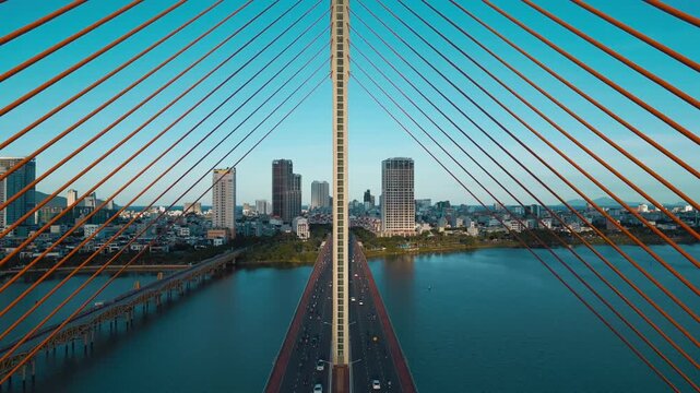 Symmetric modern cable-stayed bridge over Han River in Da Nang, Contemporary urban span connecting city skyline across Vietnamese waterway, aerial drone view 4k