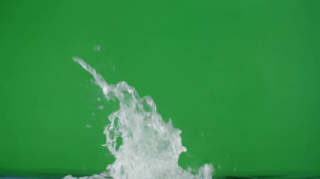 A dynamic water splash captured in slow motion against a green screen for easy chroma keying in video and special effects projects