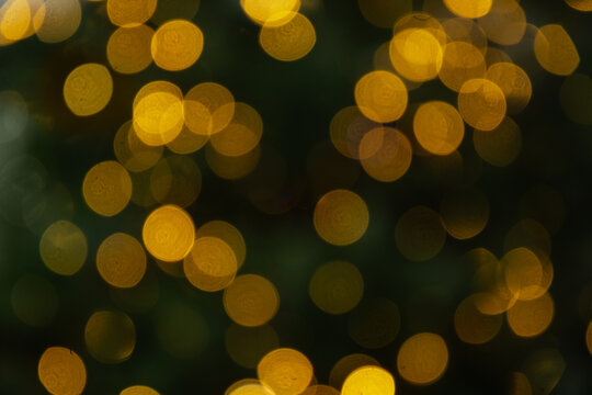 Blurred Christmas tree with golden lights garland. Abstract pattern. Defocused background. Xmas holiday spirit.
