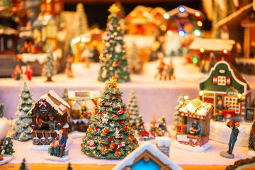 Tiny festive village with decorated trees and miniature houses illuminated by warm lights