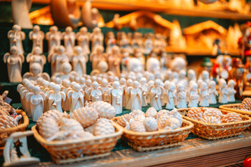 Small wooden angels arranged in rows display festive decorations and pine cones in woven baskets.