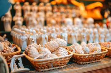 Handmade wooden angels and pine cones displayed in woven baskets at a market.