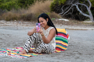 Woman with mobile phone on the beach.