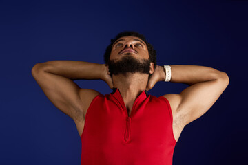 Sportive African American man exercising with focus against a vibrant blue backdrop