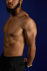 Fototapeta premium Sportive man with curly beard showcases athleticism against a blue background