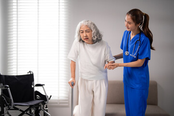 Obraz premium Asian nurse caregiver assists older adult woman walks cane medical support rehabilitation therapy home healthcare senior living