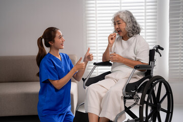 Fototapeta premium Asian adult caregiver nurse helps elderly senior patient take medication providing home health support encouraging wellbeing in a residential setting