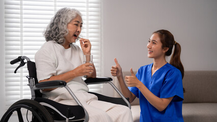 Asian elder woman taking medication nurse providing care support home health professional senior adult wellbeing daily assistance medical patient