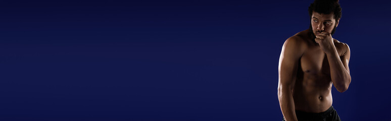 Fototapeta premium Sportive african american man focuses on workout against vibrant blue backdrop