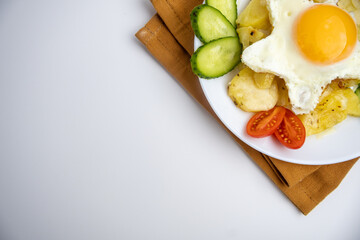 Children's breakfast with fried egg, potatoes, and vegetables. Copy space