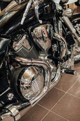 Detailed view of a shiny chrome motorcycle engine and exhaust pipes, reflecting the surroundings with precision