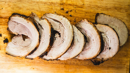 Sliced rolled pork belly chashu arranged on a wooden board, ready for ramen. Tender, marinated, and perfectly cooked. Ideal for Asian cuisine and food presentation.