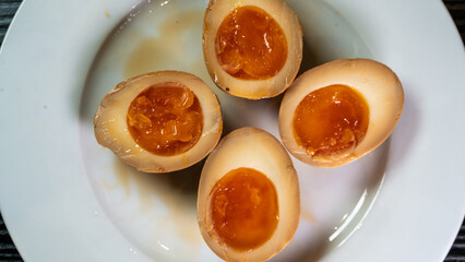 Soy-marinated ajitsuke tamago eggs halved on a plate, revealing creamy, succulent yolks. Perfect for ramen topping or appetizer. Rich, flavorful, and authentic.