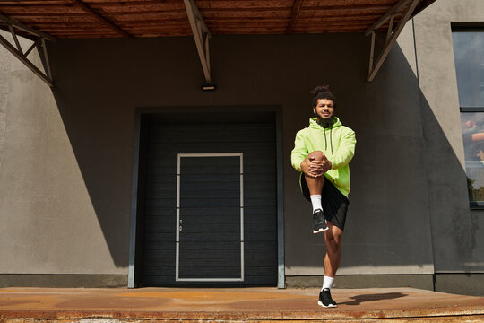 Sportive African American man warms up in vibrant green hoodie outdoors