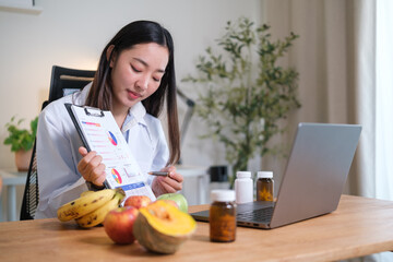 Female nutritionist explains a daily nutrition overview remotely, using data visuals while bananas, lettuce, carrots, pumpkin, and apples sit on the desk.