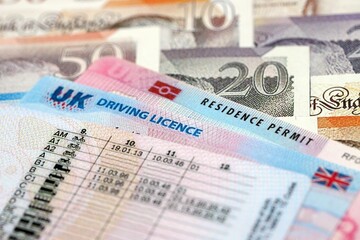United Kingdom driving license with residence permit card on UK money close up