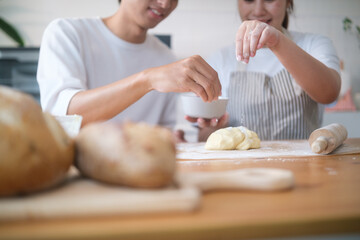 Close-up of couple sprinkling flour on dough while baking at home. Concept of teamwork, love, and homemade cooking.