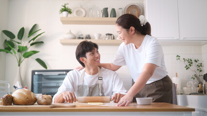 Happy couple smiling while baking together in cozy kitchen. Concept of love, domestic life, and spending quality time at home.
