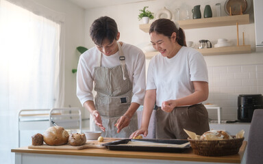 Happy couple smiling while baking together in cozy kitchen. Concept of love, domestic life, and spending quality time at home.