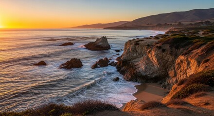 Dramatic coastal sunset over rocky ocean shoreline with waves crashing